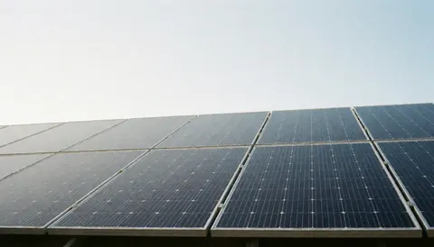 Solar panels installed on a roof against a clear blue sky, providing ample copy space for text overlays in business contexts.