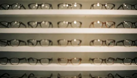 A soft, out-of-focus background featuring neatly arranged eyeglass display shelves, ideal for overlaying text or marketing content in an optical store setting.