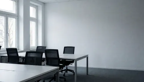 Modern minimalist office space in Berlin featuring empty tables and chairs, gray walls, and natural light, ideal for text or logo placement.