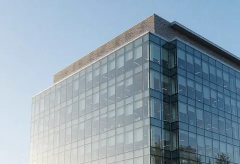 Modern office building with glass facade and clear blue sky, suitable for accounting firms and professional businesses