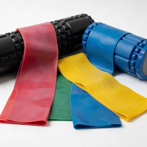 Colorful resistance bands and foam rollers arranged on a white background, ideal for physical therapy and rehabilitation product photography.
