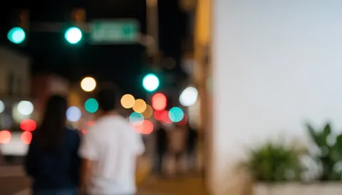 Abstract night city background with blurred traffic lights and streetlamps, white space on the right for text, ideal for urban businesses.