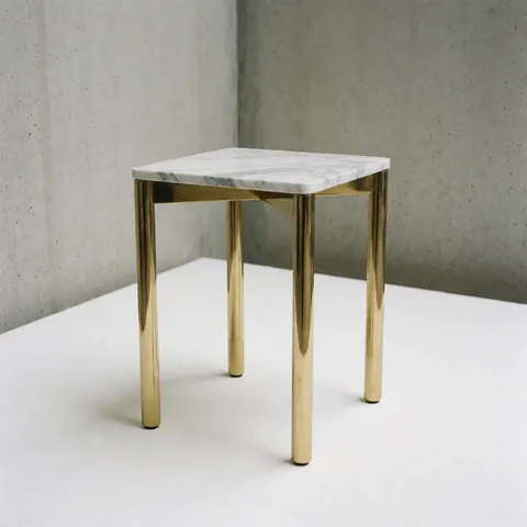 Close-up view of a sleek marble side table featuring a white stone top and elegant gold metal legs, suitable for contemporary furniture stores