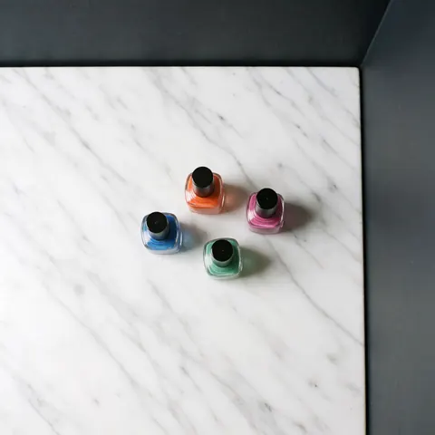 Several colorful nail polish bottles arranged neatly on a polished white marble surface for product display