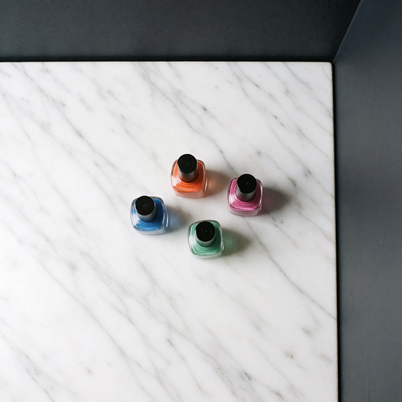 Several colorful nail polish bottles arranged neatly on a polished white marble surface for product display