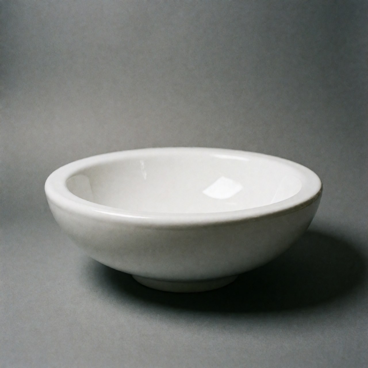 White ceramic sink on gray background with soft minimalist lighting, ideal for bathroom or kitchen decor