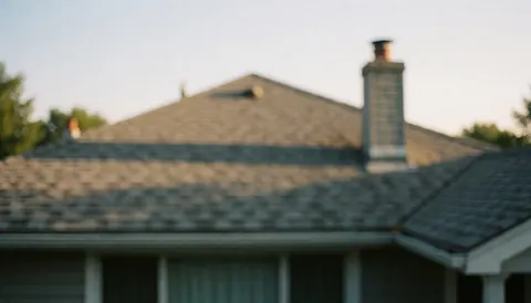 Soft focus image of a residential roof and chimney against a warm sunset sky, suitable as a text background for business presentations