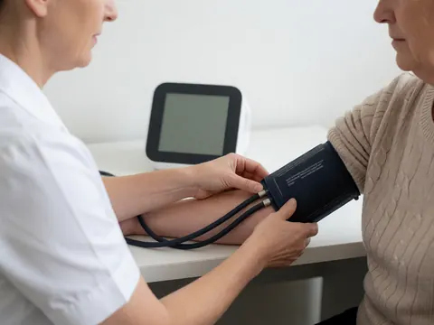 A nurse uses a digital monitor to measure a patient's blood pressure in a clean, well-lit medical clinic.
