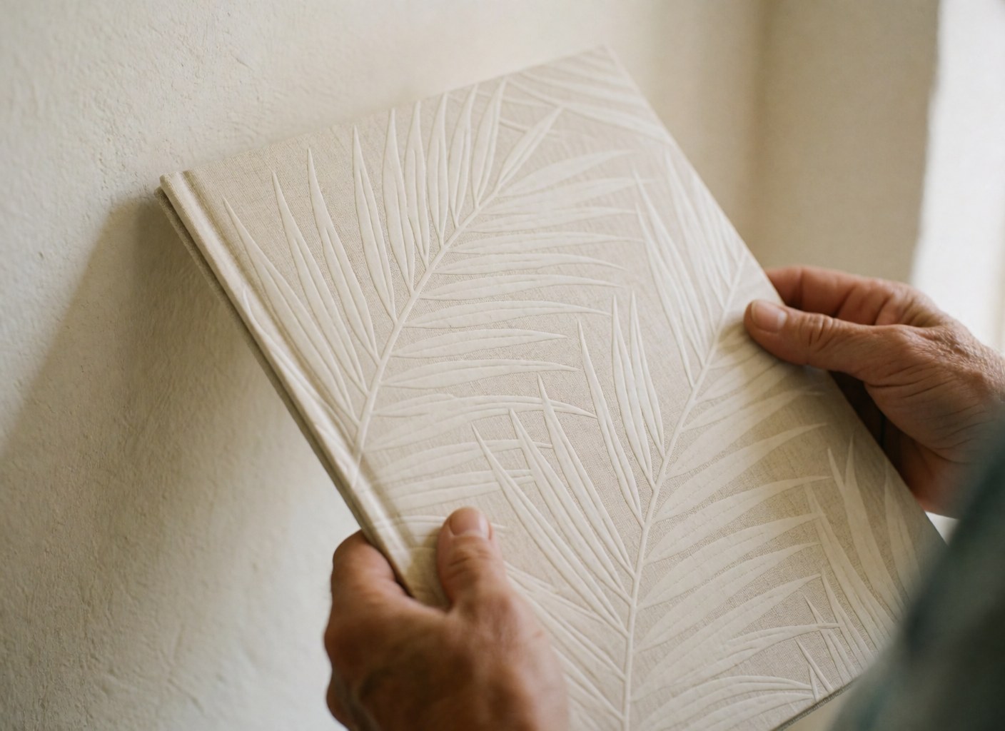 Hands holding a luxury travel brochure featuring palm leaf patterns against a white background, highlighting details for a travel agency
