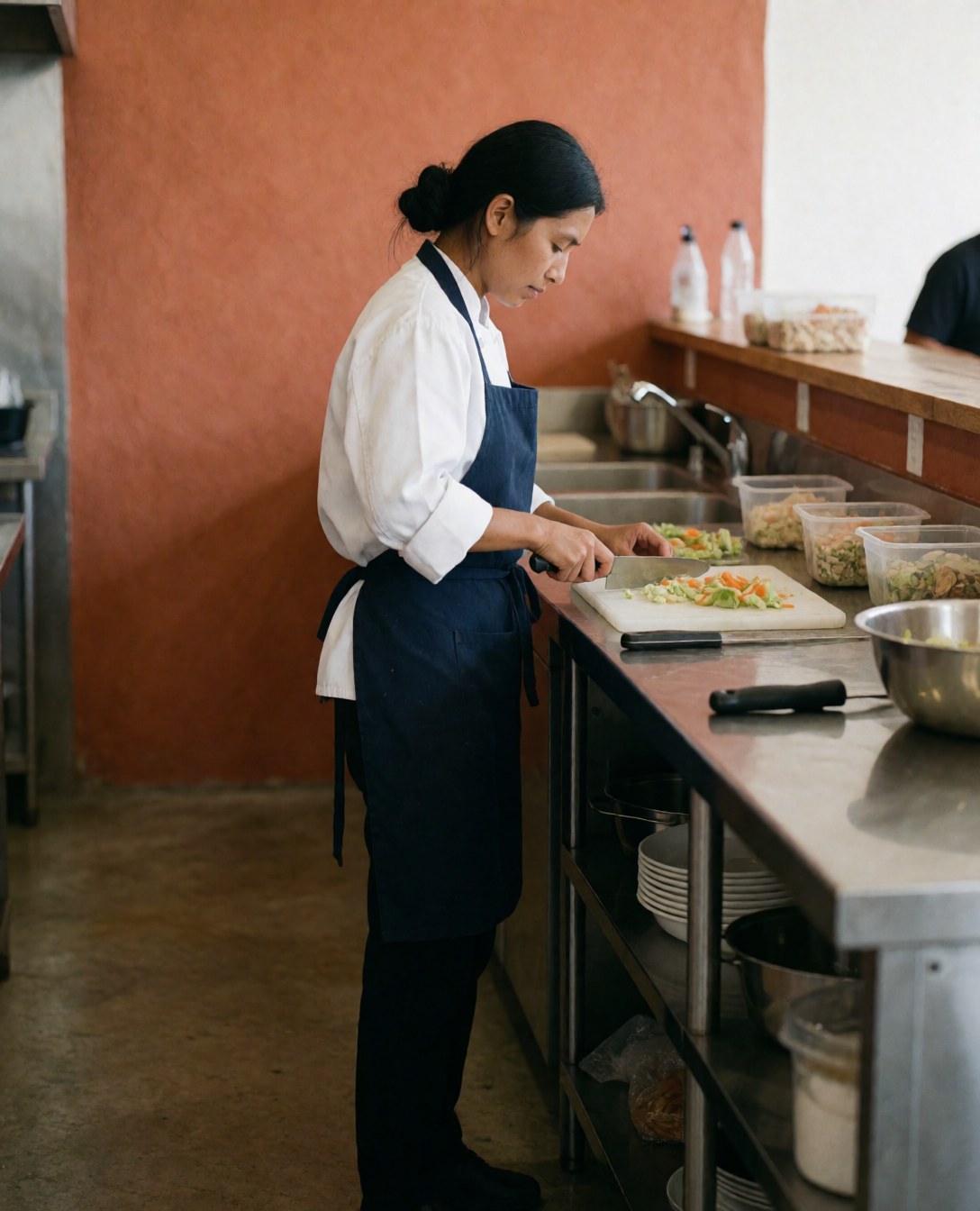 A chef carefully preparing fresh vegetables on a cutting board in a professional kitchen setting