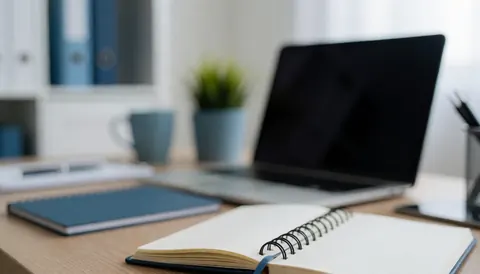 Clean modern office desk with laptop, notebook, and plants on a white and blue background for text overlay