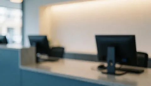 A clean and professional empty counter at a travel agency with a computer monitor and soft lighting, suitable for text overlay or advertising.