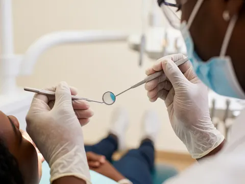 Detailed close-up view of a dental mirror and explorer tool resting on a clean white surface in a dental clinic setting
