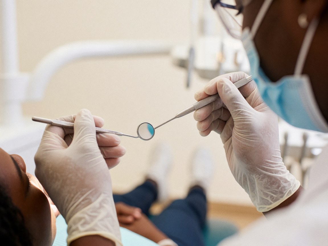 Detailed close-up view of a dental mirror and explorer tool resting on a clean white surface in a dental clinic setting