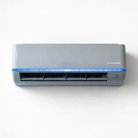 Close-up view of a sleek white indoor air conditioning unit mounted on a plain wall, showcasing its minimalist design and clean lines suitable for residential or commercial HVAC installations.