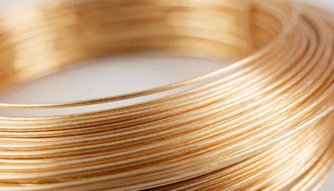 Close-up view of copper wire coils arranged on a smooth, neutral surface suitable for electrician business backgrounds