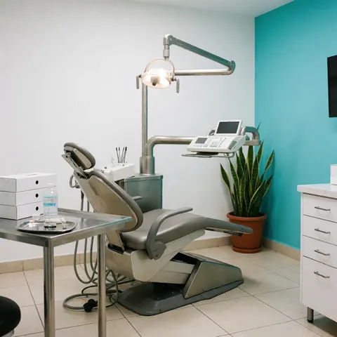 Dental camera and chair against a turquoise wall with a plant, showing a clean and professional dental clinic environment.