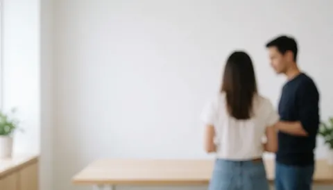 A soft focus background of a modern coworking office space featuring light wood, white walls, and green plants near a window with natural light