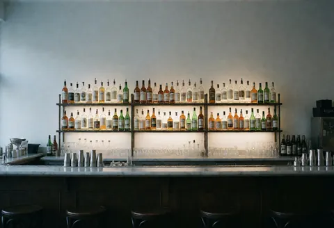 A clean and modern bar interior with wooden counter, glassware, and bottles ready for service before opening