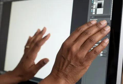 Close-up view of hands using a computer mouse to edit a photograph on a monitor screen in a professional photo studio setting