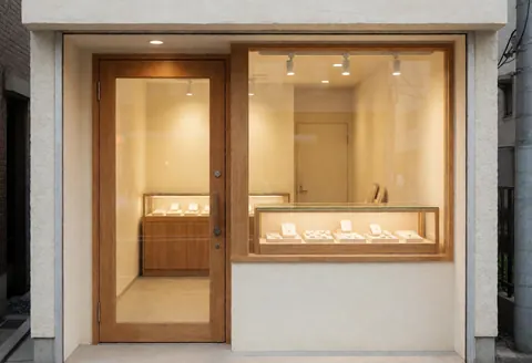 Interior view of a jewelry store featuring a wooden door, cream walls, warm lighting, and a display case creating a cozy and professional atmosphere.