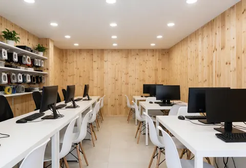 A clean and organized it support store interior featuring a wooden desk with a computer monitor, keyboard, and mouse, showcasing a professional workspace environment.