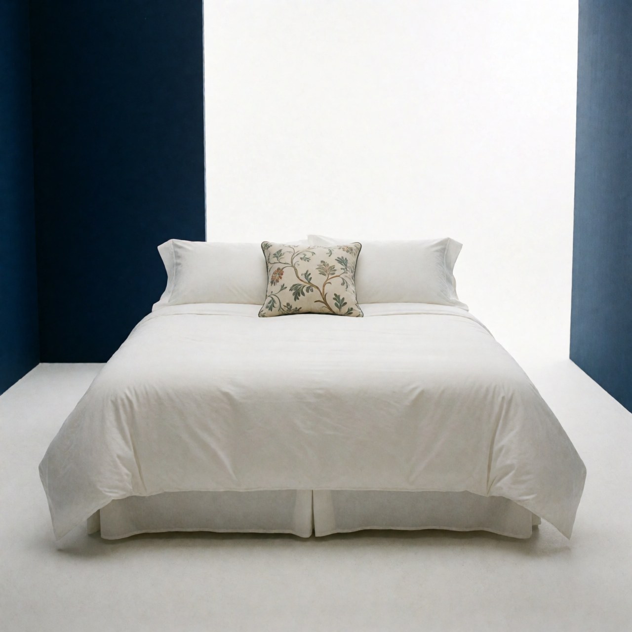 A neatly made bed featuring crisp white linens and a decorative pillow against a blue wall in a luxury hotel room