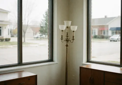 Bright interior of a furniture store with wooden and metal pieces, floor lamps, and large windows ready for customers