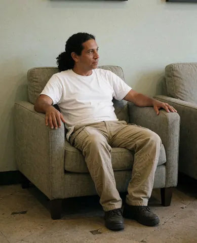 A relaxed man sitting comfortably on a stylish sofa in a modern furniture store with green walls and polished floors