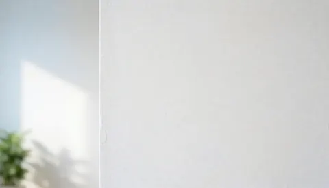 Close-up view of a clean white painted wall with subtle texture, serving as a minimalist background suitable for commercial text overlays and business presentations.
