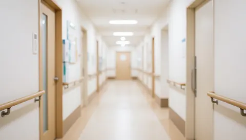 A clean and calm blurred hallway in a medical clinic with white walls, doors, and handrails, serving as a professional background for healthcare text.