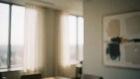 Modern office interior featuring large windows, neutral curtains, and abstract wall art on a soft background suitable for financial service text overlays
