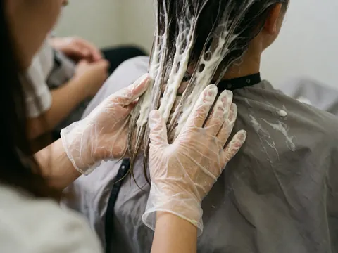 Close-up view of a professional hair treatment application featuring quinoa ingredients being applied to hair in a salon setting