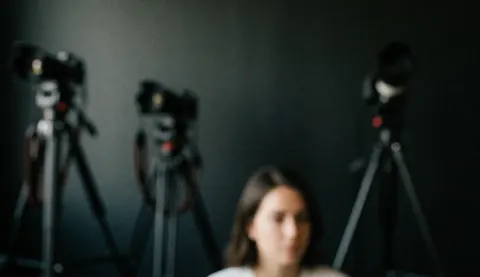 Dark studio background featuring cameras mounted on tripods with ample copy space at the top for text