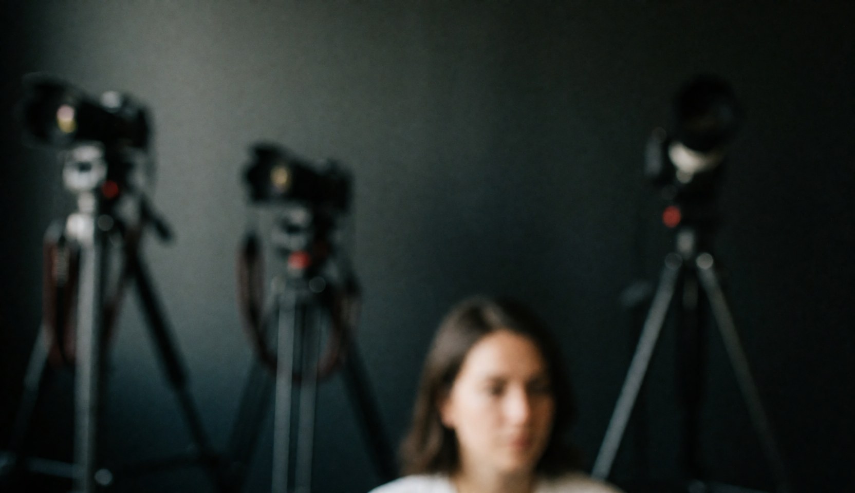 Dark studio background featuring cameras mounted on tripods with ample copy space at the top for text