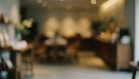 A blurred background of a sophisticated hotel lobby featuring warm ambient lights, wooden textures, and elegant interior decor suitable for text overlays