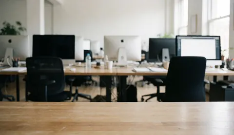 Clean modern office desk with computer and chair near a window with natural light, professional background for text