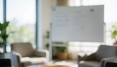 A modern office space featuring chairs, a whiteboard, and natural light, with a blurred background suitable for text overlay in marketing materials.