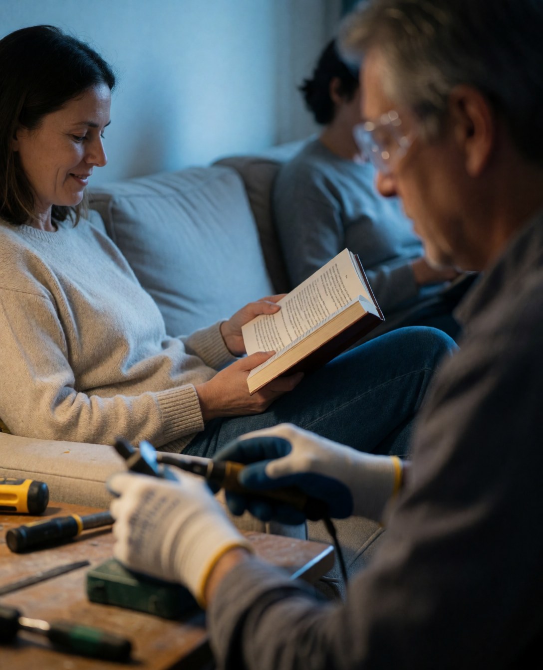 A relaxed woman sitting comfortably on a sofa in a cool room, enjoying the fresh air conditioning while reading a book at home.