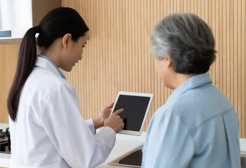 A female inspector holds a tablet while explaining details to an older female client in a modern kitchen with natural light.