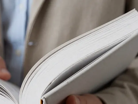 A close-up view of hands holding a thick language learning textbook with visible pages, ideal for educational and language school contexts