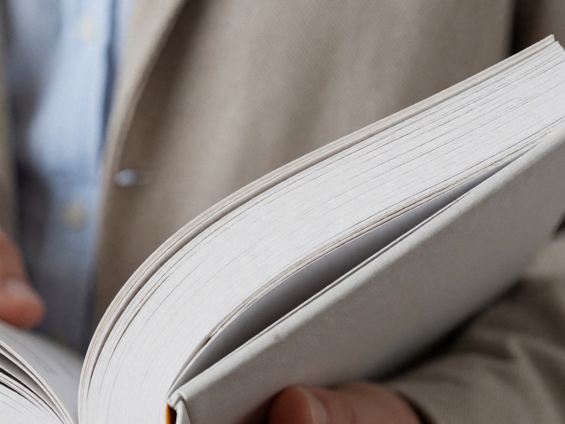 A close-up view of hands holding a thick language learning textbook with visible pages, ideal for educational and language school contexts