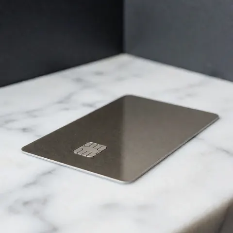 A detailed close-up view of a modern metallic credit card with a minimalist design, highlighting its premium texture and professional appearance for business use.