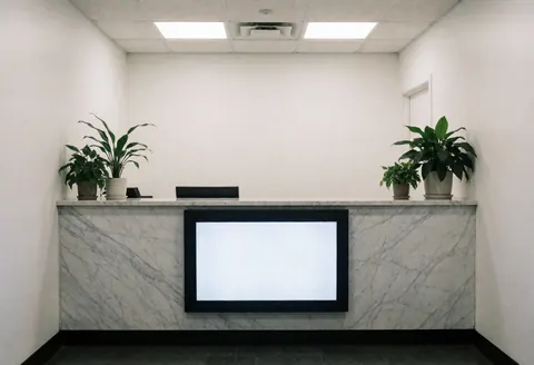 Clean and professional insurance agency reception featuring a marble counter, digital screen, and plants in a well-lit interior space.
