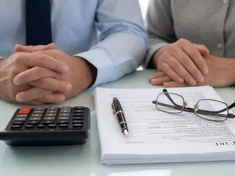 Professional desk setup featuring a calculator, pen, glasses, and accounting documents for business use