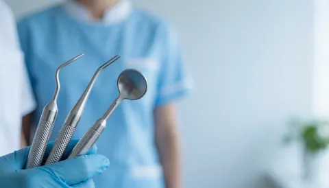 Abstract close-up view of professional dental tools and equipment arranged on a clean, sterile surface for use as a background in dental clinic marketing materials