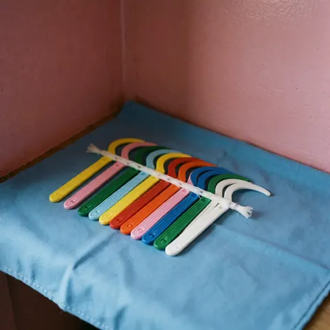 Blue dental floss and floss picks arranged neatly on a pink surface for daily oral hygiene and dental care