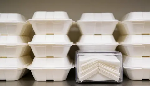 Blurred background of fast food containers and a napkin dispenser, ideal for restaurant advertising and text overlays.