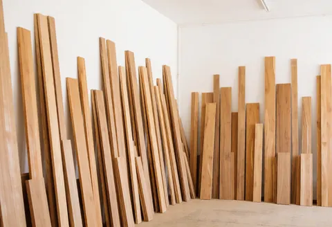 A tidy carpentry workshop interior featuring organized stacks of light natural wood boards and construction panels ready for use.