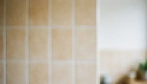A blurred kitchen background with warm tones, featuring clean tiles and a minimalist design, ideal for text overlay in fast food business contexts.